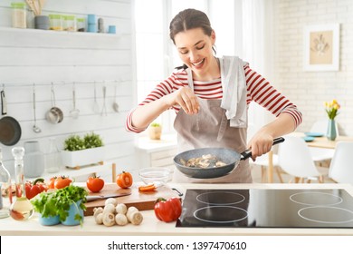 Здоровое питание дома. Счастливая женщина готовит еду на кухне.