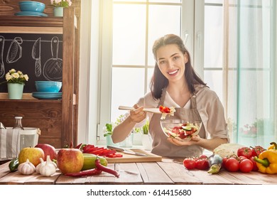 Healthy food at home. Happy woman is preparing the vegetables and fruit in the kitchen.