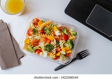 Healthy Food In Lunch Box, On Working Table With Laptop .Ensalada De Pasta Brocoli Con Queso Y Verduras. Eating At Workplace. Home Food For Office Concept 