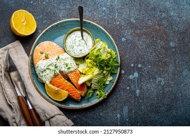 Healthy Food Meal Cooked Grilled Salmon Steaks With White Dill Sauce And Salad Leafs On Plate On Rustic Concrete Stone Background Table Flat Lay From Above, Diet Healthy Nutrition Dinner Copy Space