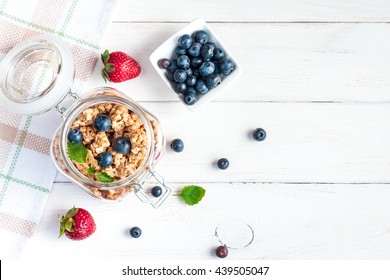 Healthy Food. Muesli In The Jar, Blueberry And Strawberry On White Wooden Background, Top View, Flat Lay