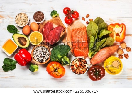 Healthy food products. Balanced nutrition. Salmon fish, beef, beans, nuts and vegetables with olive oil. Top view image at white table.