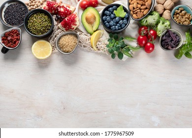 Healthy food selection on white wooden background . Fresh fruits , superfoods an vegatables . High in antioxidants, vitamins, minerals, fiber. Top view with copy space .