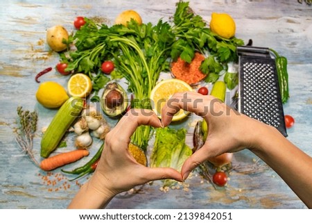 Healthy food with vegetables and fruits. A girl hands making heart sign. Healthy life, diet, loving yourself and balanced nutrition. Background. No people.