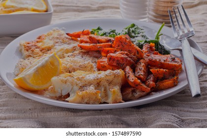 Healthy Food,lightly Battered Cod With Sweet Potato Wedges,there Is Spinach On The Plate As Well,there Is Some Lemon Wedges In The Background.  