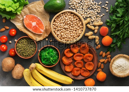 Healthy foods high in potassium. A variety of legumes, salmon, fruits, vegetables, dried apricots, seaweed chuka and nuts on a dark background. Top view, flat lay Stock foto © 