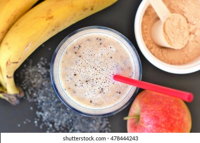 Healthy Fresh Smoothie Drink From Red Apple, Banana Chia Seeds And Plant Protein Powder In The Glass With Straw On Black Background, Overhead Horizontal View