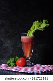 Healthy Freshly Made Tomato And Celery Vegetable Juice On Vintage Style Red Check Napkin Against Black Slate Kitchen Bench Top.