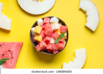 Healthy Fruit Salad Of Watermelon, Melon And Peach In Coconut Bowl In Hands Of Child On Yellow Background. View From Above. Clean Eating, Vegetarian Food Concept.