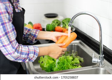healthy girl Washing vegetables in the kitchen sink - Shutterstock ID 1705258837