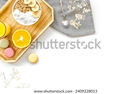 Healthy granola in bowl , macaroons and orange juice in glass for colorful breakfast on white background top view mock-up