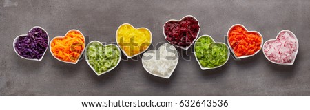 Healthy grated vegetables of different colors in heart-shaped bowls in funny long row as wide banner concept