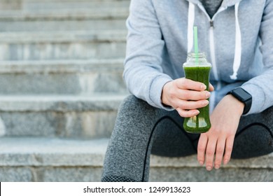 Healthy green juice detox smoothie drink woman. Girl holding glass bottle of cold pressed vegetable, juicing trend for nutrition cleanse.