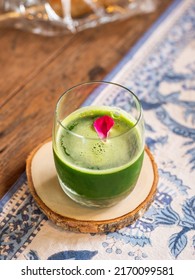 Healthy Green Smoothie In A Clear Glass Garnished With Rose Petals. A  Cup Of Healthy Drinks Made From Kale And Fruit Juice, Selective Focus.