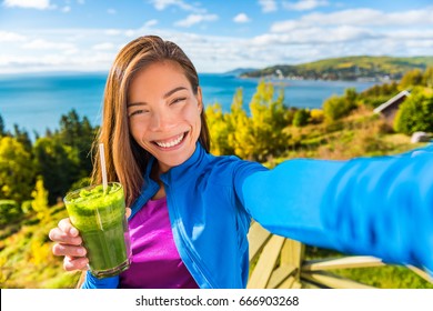 Healthy Green Smoothie Juice Drinking Selfie Girl Taking Picture Or Video Vlog For Social Network Of Clean Food Diet. Asian Woman Eating Spinach Vegetable Juicing In Beautiful Outdoors Nature.