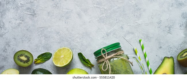 Healthy green smoothie in mason jar and ingredients. Superfoods, detox, diet, healthy food. Lime, apple, spinach, avocado and lime. Green food background.