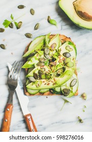 Healthy Green Veggie Breakfast Concept. Sandwich With Avocado, Cucumber, Kale, Kress Sprouts, Pumpkin Seeds Over Marble Background, Top View. Vegan, Weight Loss, Detox, Vegetarian, Diet Food Concept