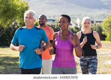 Healthy group of mature people jogging on track at park. Happy senior couple running at park with african friends. Multiethnic middle aged friends exercising together outdoor.