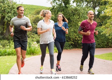 Healthy group of people jogging on track in park. Happy couple enjoying friend time at jogging park while running. Mature friends running together outdoor. - Shutterstock ID 613868252