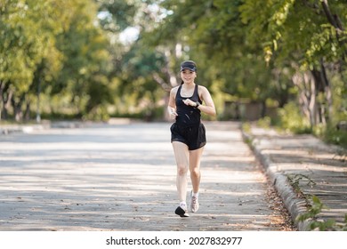 A Healthy Happy Asian Woman Runner In Black Sport Outfits Jogging In The Natural City Park Under Evening Sunset