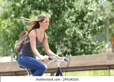 Healthy and happy cyclist woman riding fast a bicycle in a park
