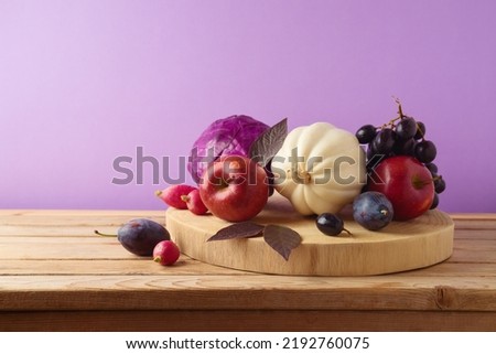 Healthy harvest concept.  Pumpkin, apple, grapes and vegetables on wooden log.  Autumn still life