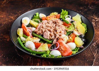 Healthy hearty salad with tuna, green beans, tomatoes, eggs, potatoes and black olives in a plate. Dark background. top view - Shutterstock ID 1953969316