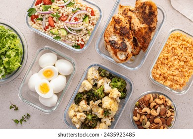Healthy high protein meal prep with cooked chicken breast, boiled eggs, roasted vegetables, cooked lentils, couscous salad and mixed nuts