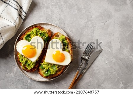 Healthy holidays breakfast with eggs hearts, croissants and cup of coffee on grey background, top view, copy space