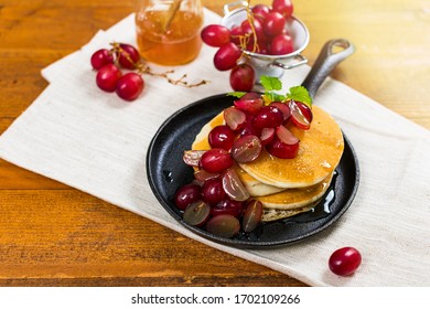Healthy Homemade Classic American Pancakes with Sliced Red Grapes and Maple Syrup Close Up. Selective focus.