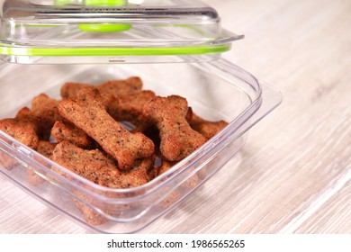 Healthy Homemade Dog Bone-shaped Cookies Treats Biscuits In Transparent Food Storage Container, Over Light Wooden Background