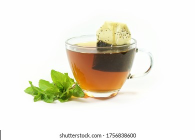 Healthy Hot Drink, Herbal Tea Bag In A Glass Cup And A Few Fresh Peppermint Leaves Isolated On A White Background, Copy Space, Selected Focus