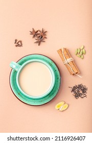 Healthy Indian Beverage Masala Chai - Tea Hot Drink With Milk And Spices In Rustic Green Teacup With Ingredients For Making Masala Chai From Above On Simple Beige Minimal Background 