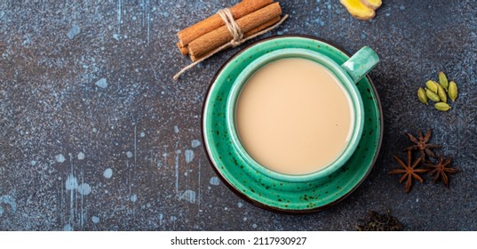 Healthy Indian Beverage Masala Chai - Tea Hot Drink With Milk And Spices In Rustic Green Teacup With Ingredients For Making Masala Chai From Above On Concrete Blue Background Copy Space