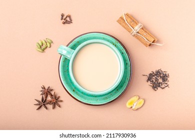 Healthy Indian Beverage Masala Chai - Tea Hot Drink With Milk And Spices In Rustic Green Teacup With Ingredients For Making Masala Chai From Above On Simple Beige Minimal Background 