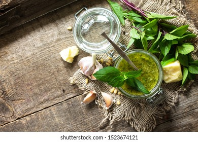 Healthy Italian cuisine. Green pesto sauce with ingredients on rustic wooden table. Top view of a flat lay. Free space for your text.