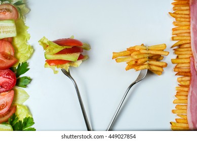 Healthy or junk food choice. Two forks: one with french fries and another with fresh vegetables