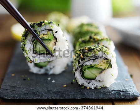 healthy kale and avocado sushi roll with chopsticks
