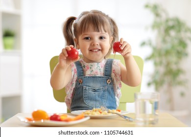 Healthy kids nutrition concept. Cute toddler girl sitting at table with plate of salad, vegetables, pasta in room. Child eating healthy food. - Shutterstock ID 1105744631