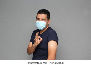 Healthy Latino Adult Man With Mask Showing His Arm That Recently Received The Covid-19 Vaccine
