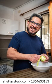 Healthy Latino Man Living With HIV Peeling An Apple In His Kitchen