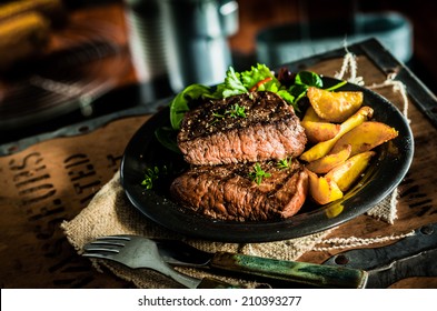 Healthy lean grilled medium-rare beef steak and vegetables with roasted pumpkin and a leafy green herb salad in a rustic pub or tavern - Shutterstock ID 210393277