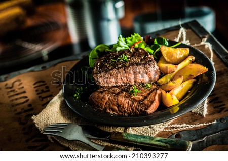 Healthy lean grilled medium-rare beef steak and vegetables with roasted pumpkin and a leafy green herb salad in a rustic pub or tavern