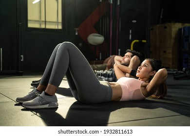 Healthy lifestyle of athletic young couple, Caucasian man and Asian woman, workout together, both doing sit ups on the gym floor. Active warmup exercise in indoor fitness for abs muscles and slim body - Powered by Shutterstock