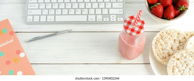 Healthy lifestyle banner. Laptop, cup of coffee, strawberries smoothie  and rice waffles on white wooden table. Top view, flat lay. copy space - Powered by Shutterstock