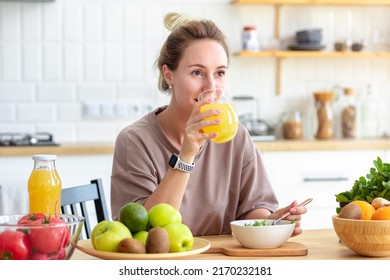 Healthy Lifestyle. Beautiful Happy Woman Drinking Juice During Breakfast. Beautiful Female Drink Fresh Juice And Eating Fresh Salad While Sitting In Her Kitchen. Vegan Meal 