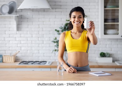 Healthy lifestyle concept. Happy young African American woman holding bottle of dietary supplements or vitamins in her hands