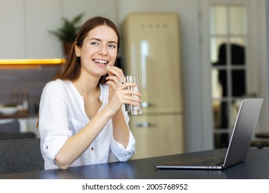 Gesunder Lebensstil Happy junge kaukasische Frau mit einem Glas Wasser Getränke Vitamine für geistige Aufmerksamkeit oder Schmerzmittel sitzen zu Hause Büro, lächelnd