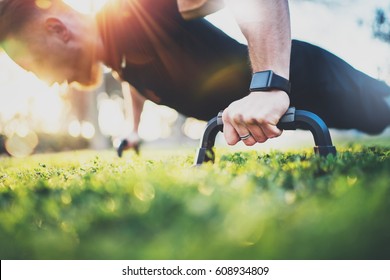 Healthy lifestyle concept.Training outdoors.Handsome sport man doing crossfit pushups in the park on the sunny morning. Blurred background