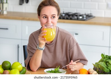 Healthy Lifestyle, Diet, Weight Loss Concept. Beautiful Happy Woman Drinking Juice During Breakfast. Beautiful Female Drink Fresh Juice And Eating Fresh Salad While Sitting In Her Kitchen. Vegan Meal 